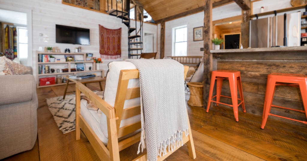 Rustic cabin interior with a spiral staircase, cosy seating area, and kitchen island.